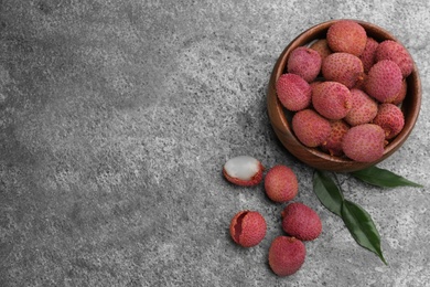 Fresh ripe lychee fruits on grey table, flat lay. Space for text