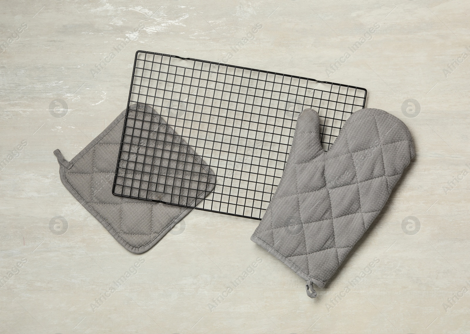 Photo of Oven mitt, potholder and cooling rack on grey table, flat lay. Cooking utensils