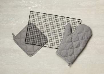 Oven mitt, potholder and cooling rack on grey table, flat lay. Cooking utensils