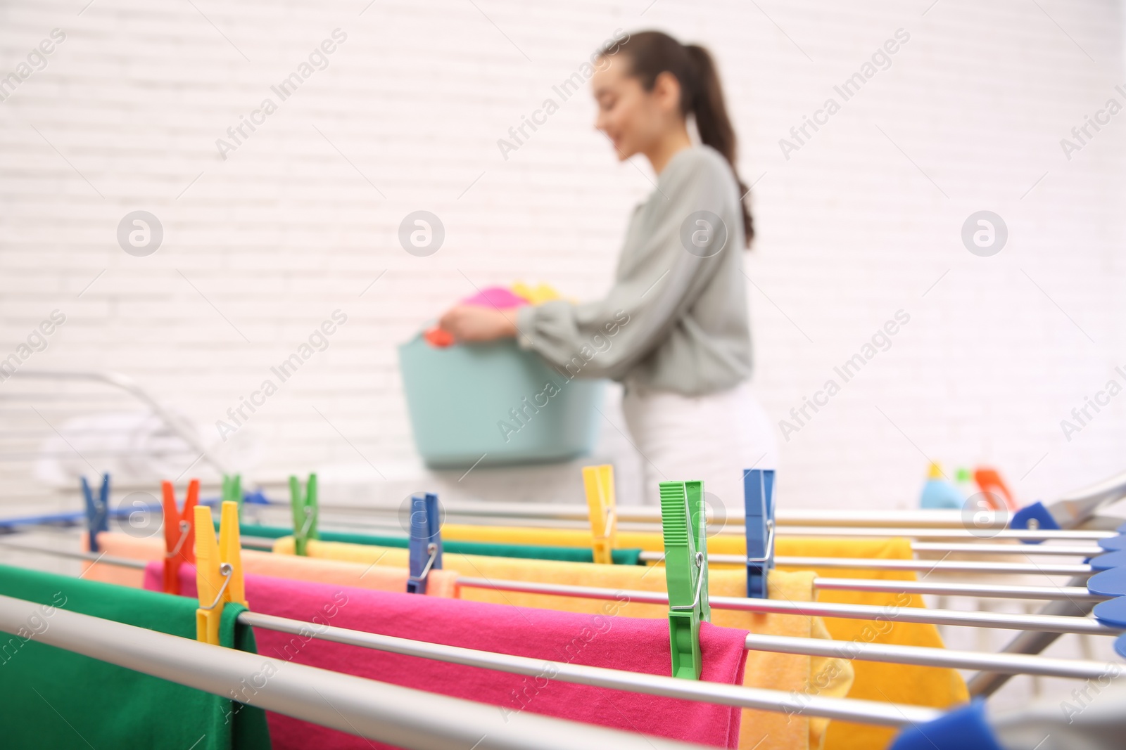 Photo of Woman with laundry basket indoors, focus on drying rack. space for text