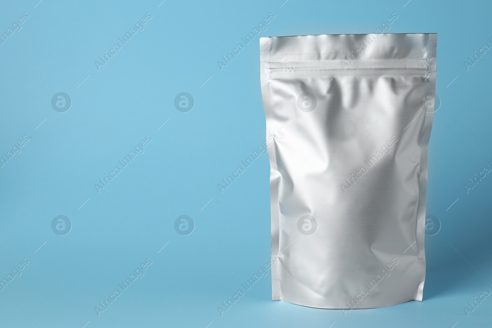 Photo of One blank foil package on light blue background. Space for text