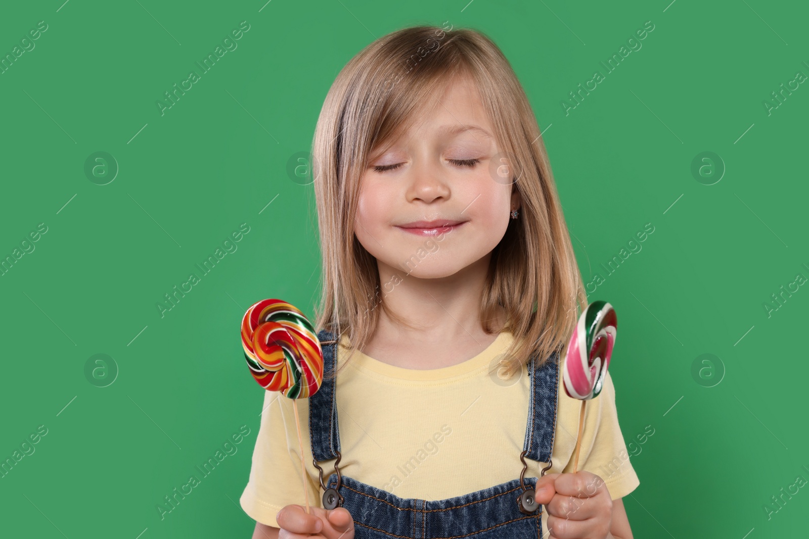 Photo of Portrait of cute girl with lollipops on green background