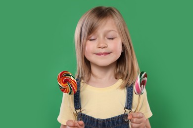 Portrait of cute girl with lollipops on green background
