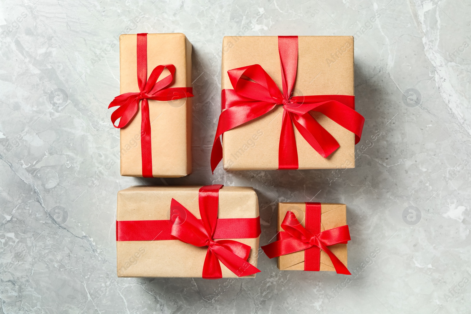 Photo of Christmas gift boxes with red bows on light grey marble background, flat lay