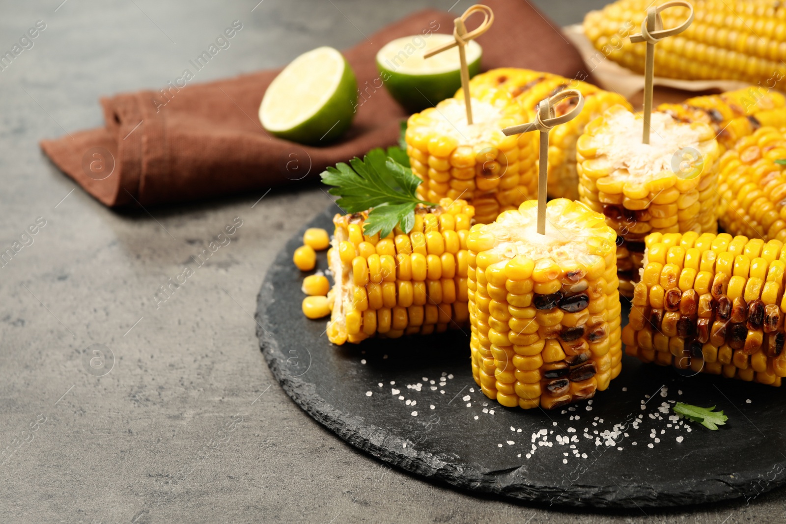 Photo of Composition with tasty grilled corn on grey table