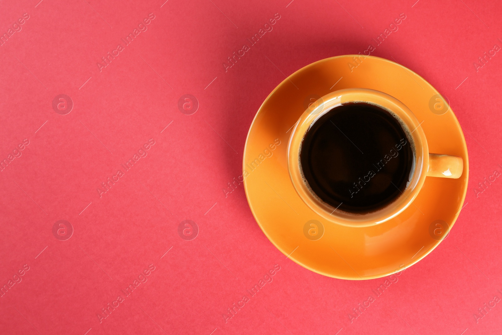 Photo of Coffee in cup on red background, top view. Space for text