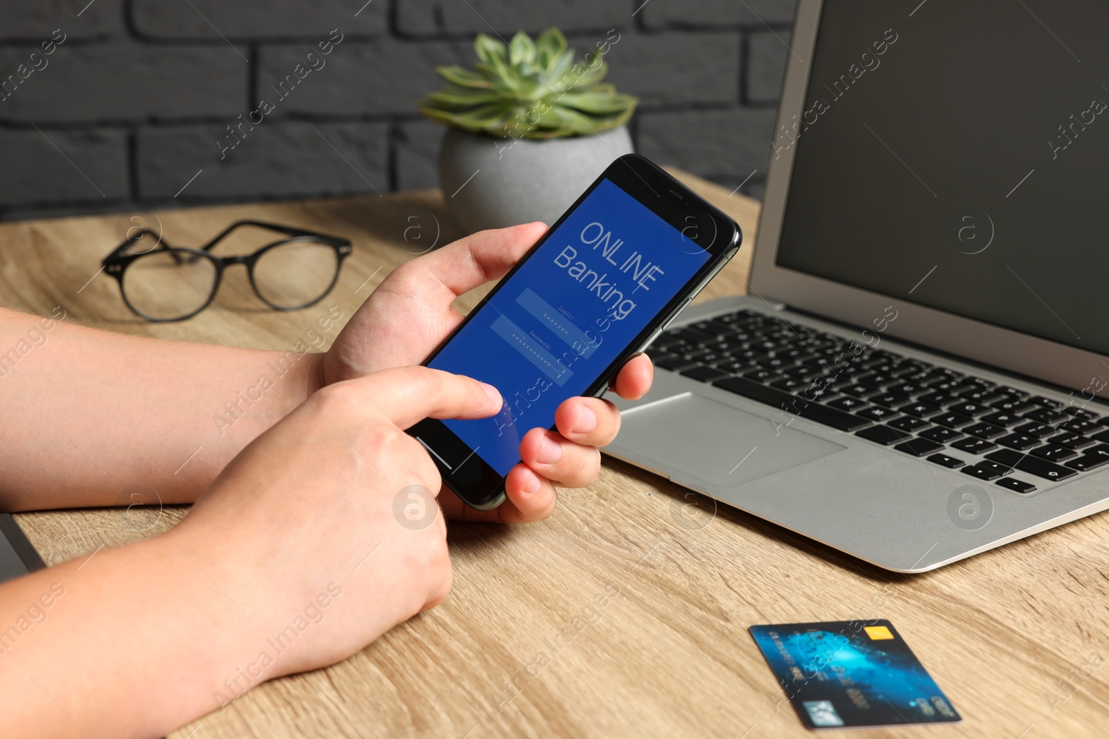 Photo of Man using online banking app on smartphone at wooden office table, closeup