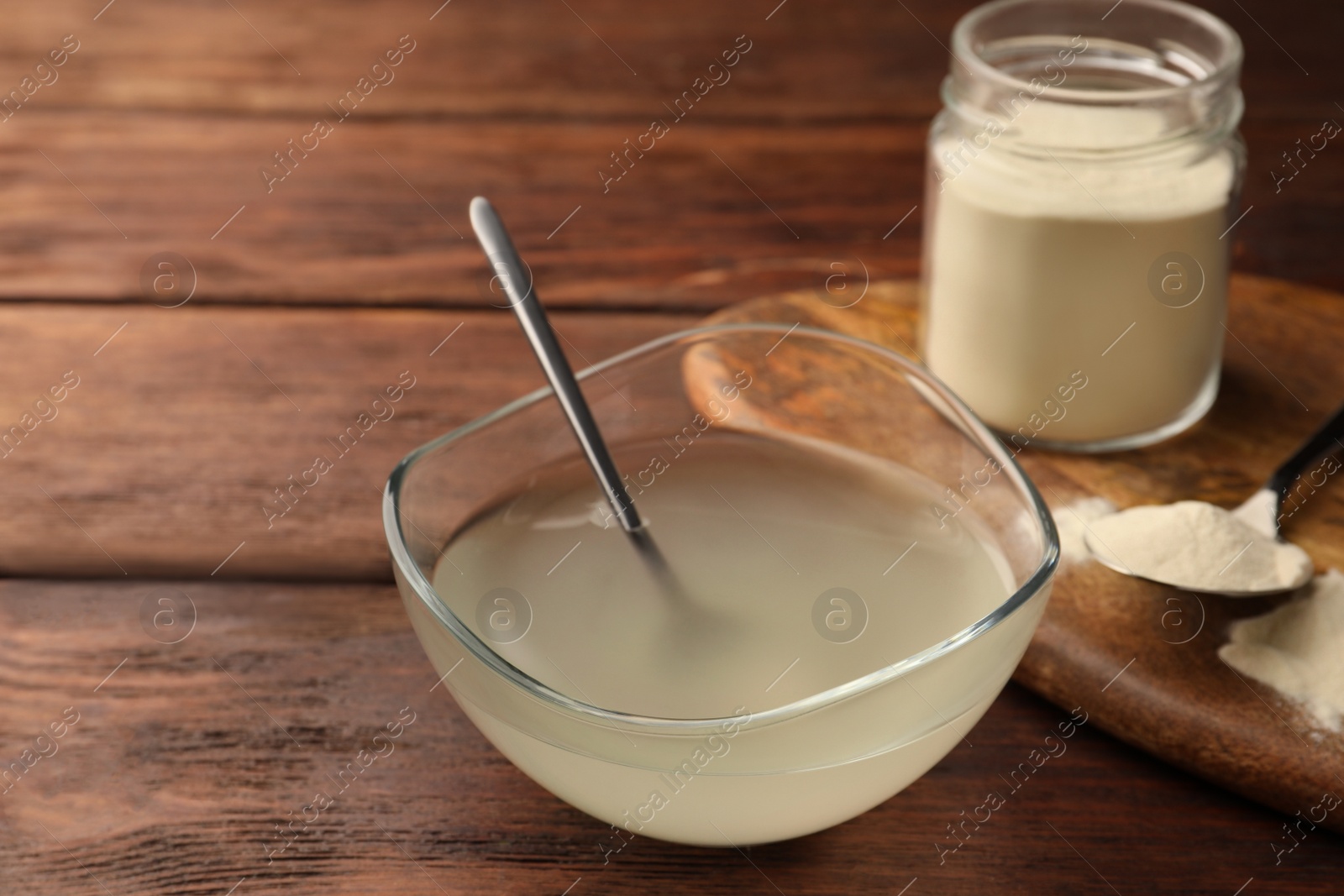 Photo of Glass bowl of agar-agar jelly and powder on wooden table. Space for text