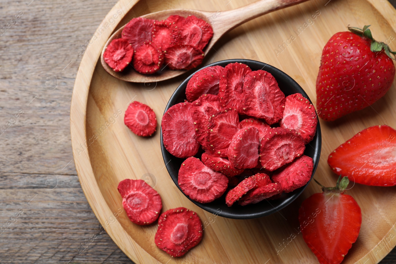 Photo of Freeze dried and fresh strawberries on wooden table, top view