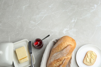 Tasty fresh bread with butter and jam on light marble table, flat lay. Space for text