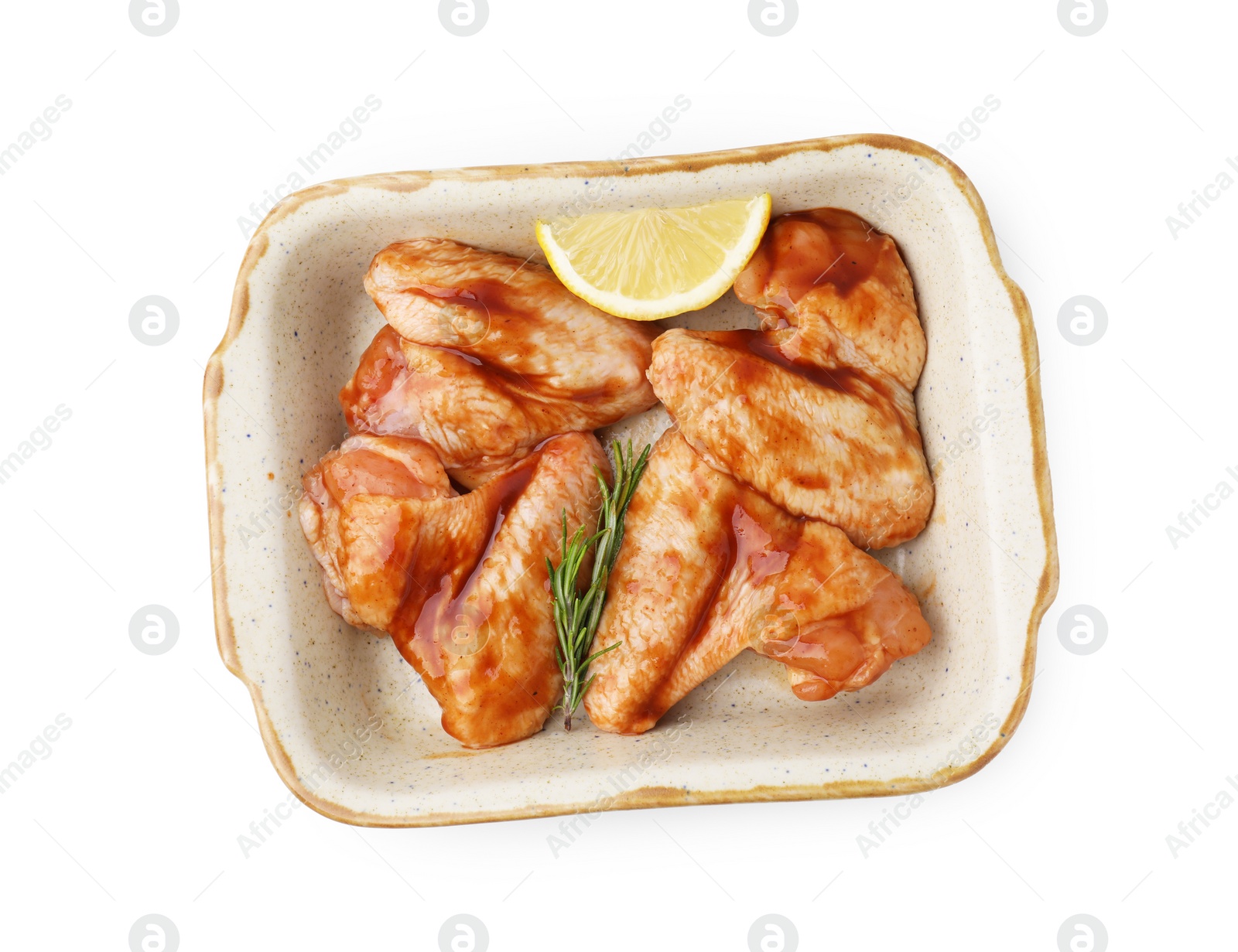 Photo of Raw marinated chicken wings, rosemary and lemon in baking dish isolated on white, top view