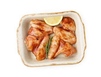 Photo of Raw marinated chicken wings, rosemary and lemon in baking dish isolated on white, top view