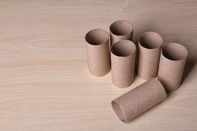 Photo of Empty toilet paper rolls and space for text on wooden background