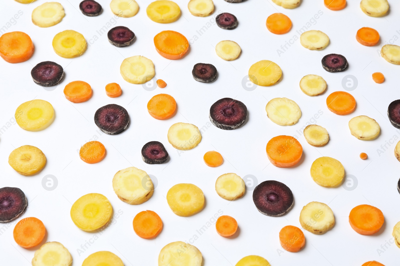 Photo of Slices of raw color carrots on white background