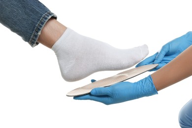 Orthopedist fitting insole to patient's foot on white background, closeup