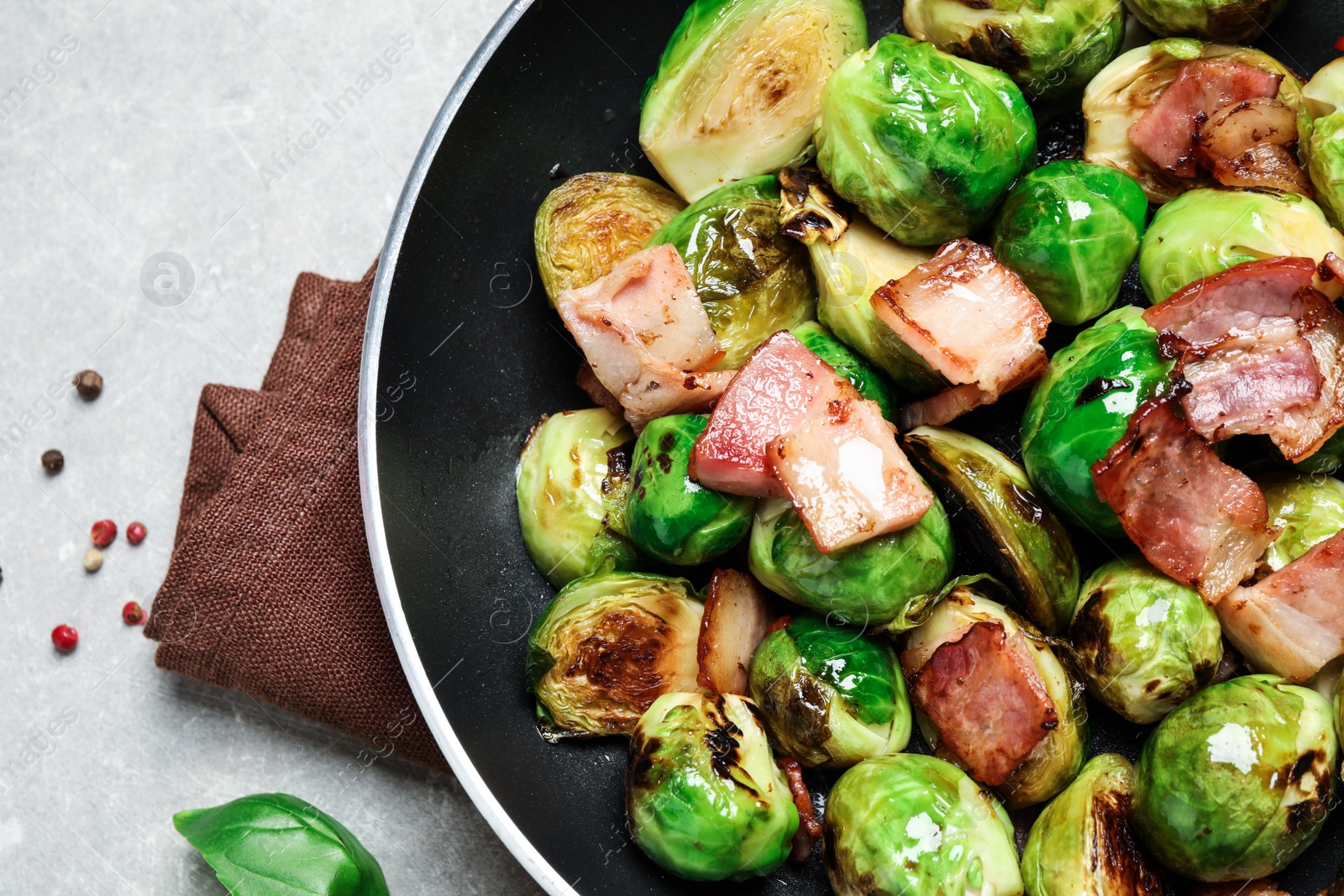 Photo of Delicious Brussels sprouts with bacon in pan on light table, closeup