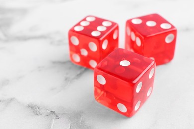 Photo of Three red game dices on white marble table, closeup. Space for text