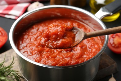 Photo of Eating homemade tomato sauce at dark table, closeup