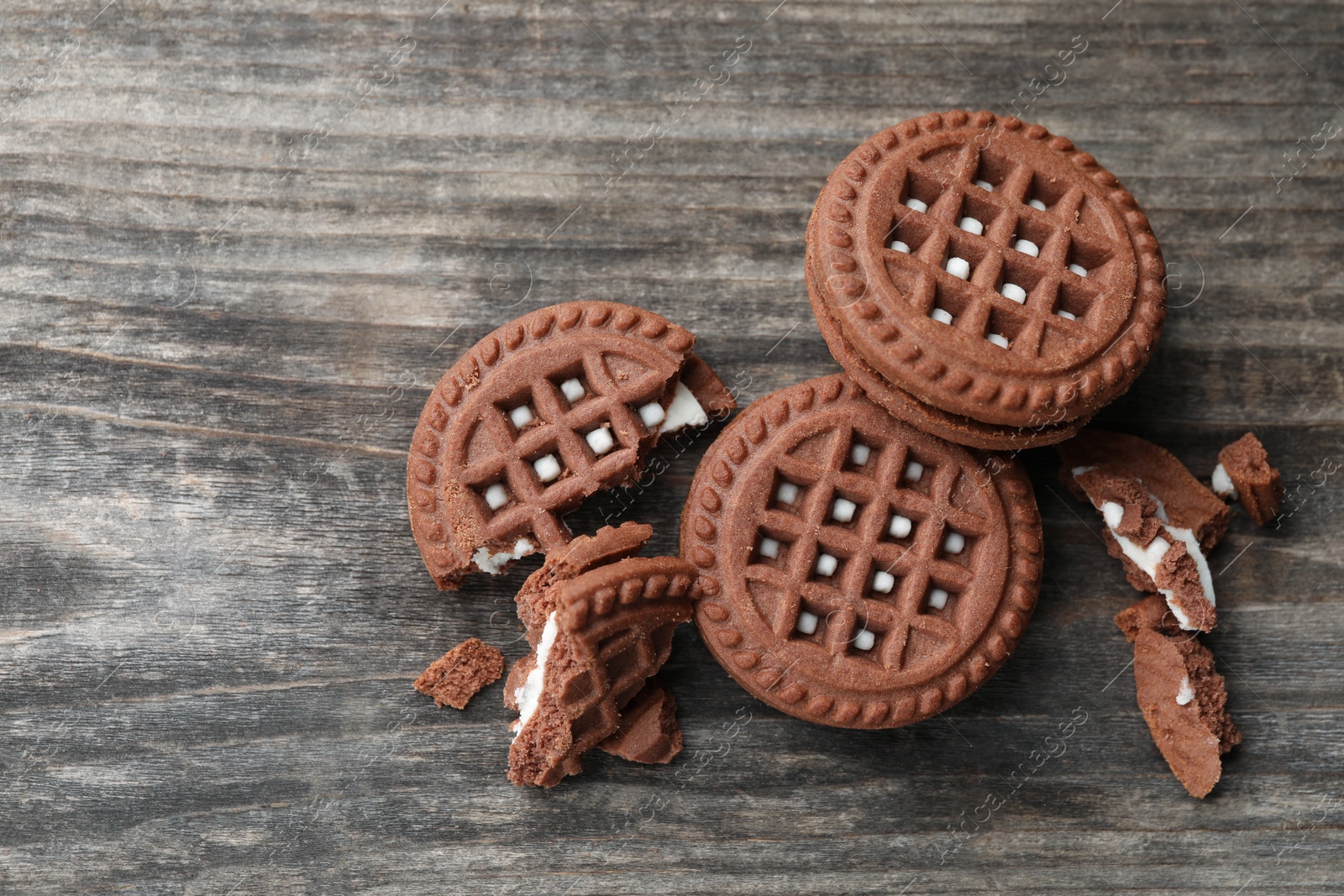 Photo of Tasty chocolate sandwich cookies with cream on wooden table, flat lay
