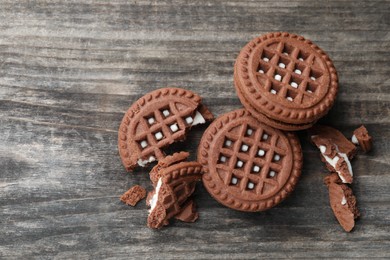 Tasty chocolate sandwich cookies with cream on wooden table, flat lay