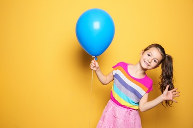 Photo of Cute girl with balloon on color background. Birthday celebration