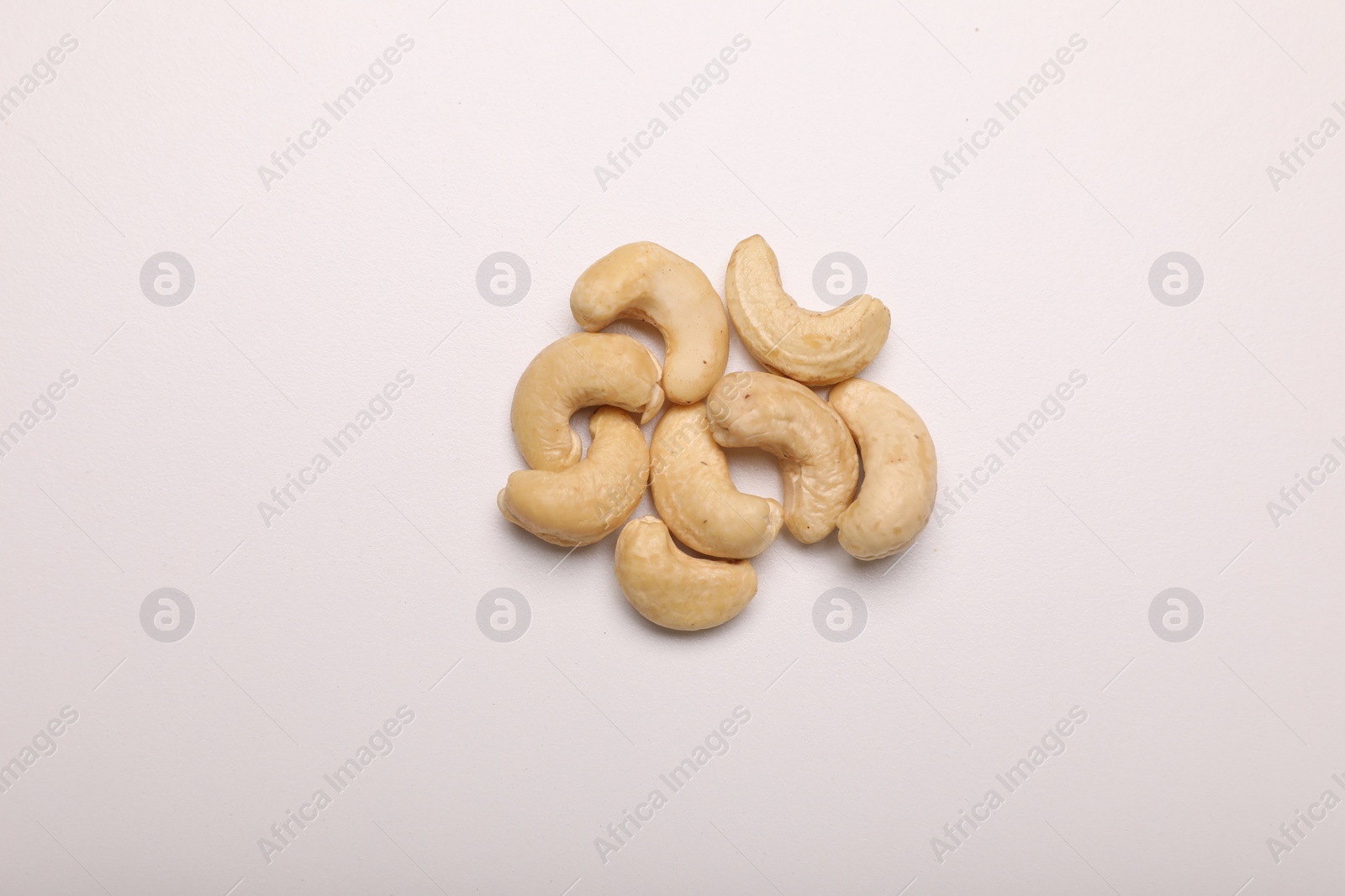 Photo of Many tasty cashew nuts on white background, top view