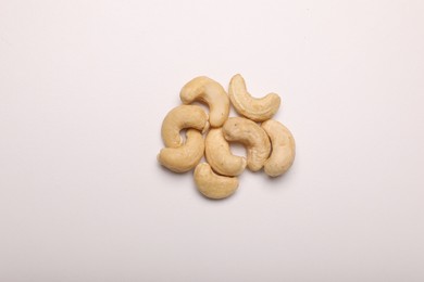 Many tasty cashew nuts on white background, top view