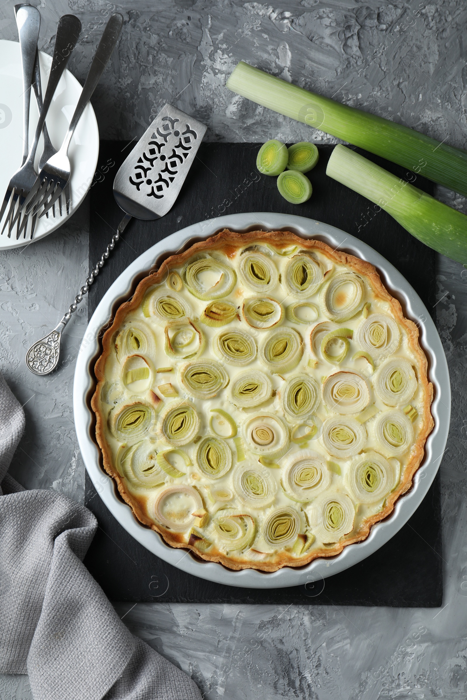 Photo of Freshly baked leek pie served on grey textured table, flat lay