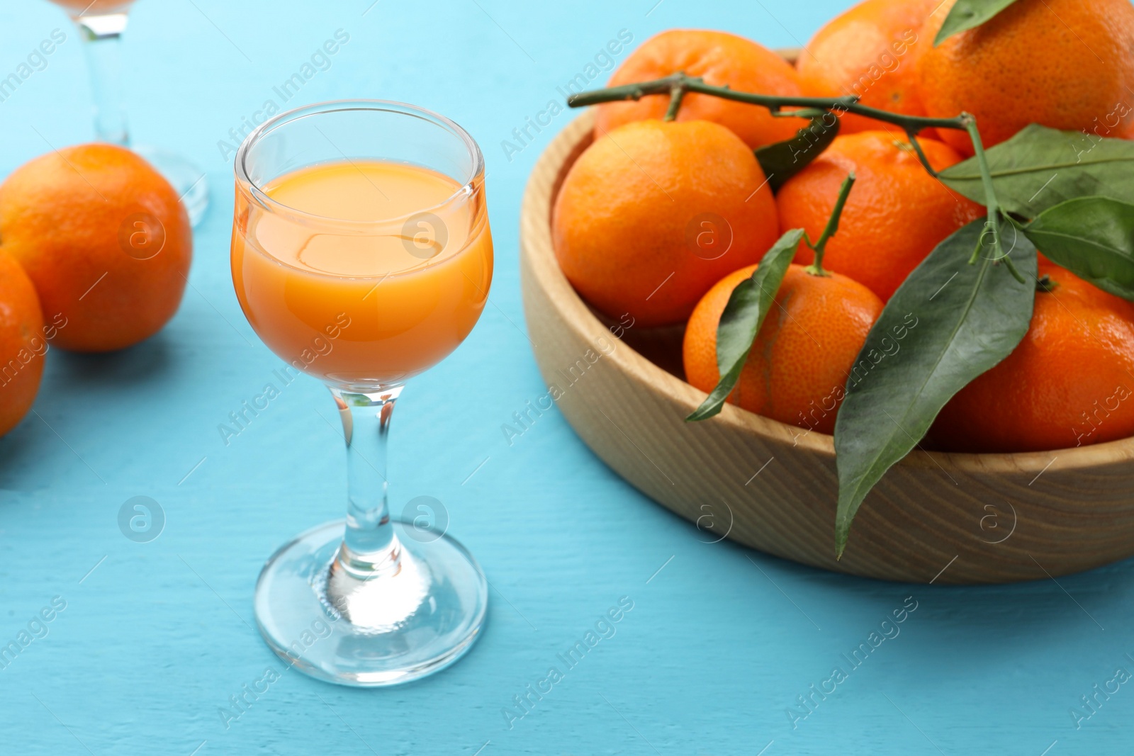 Photo of Delicious tangerine liqueur and fresh fruits on light blue wooden table