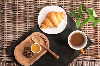 Tasty breakfast with freshly baked croissant on wicker background