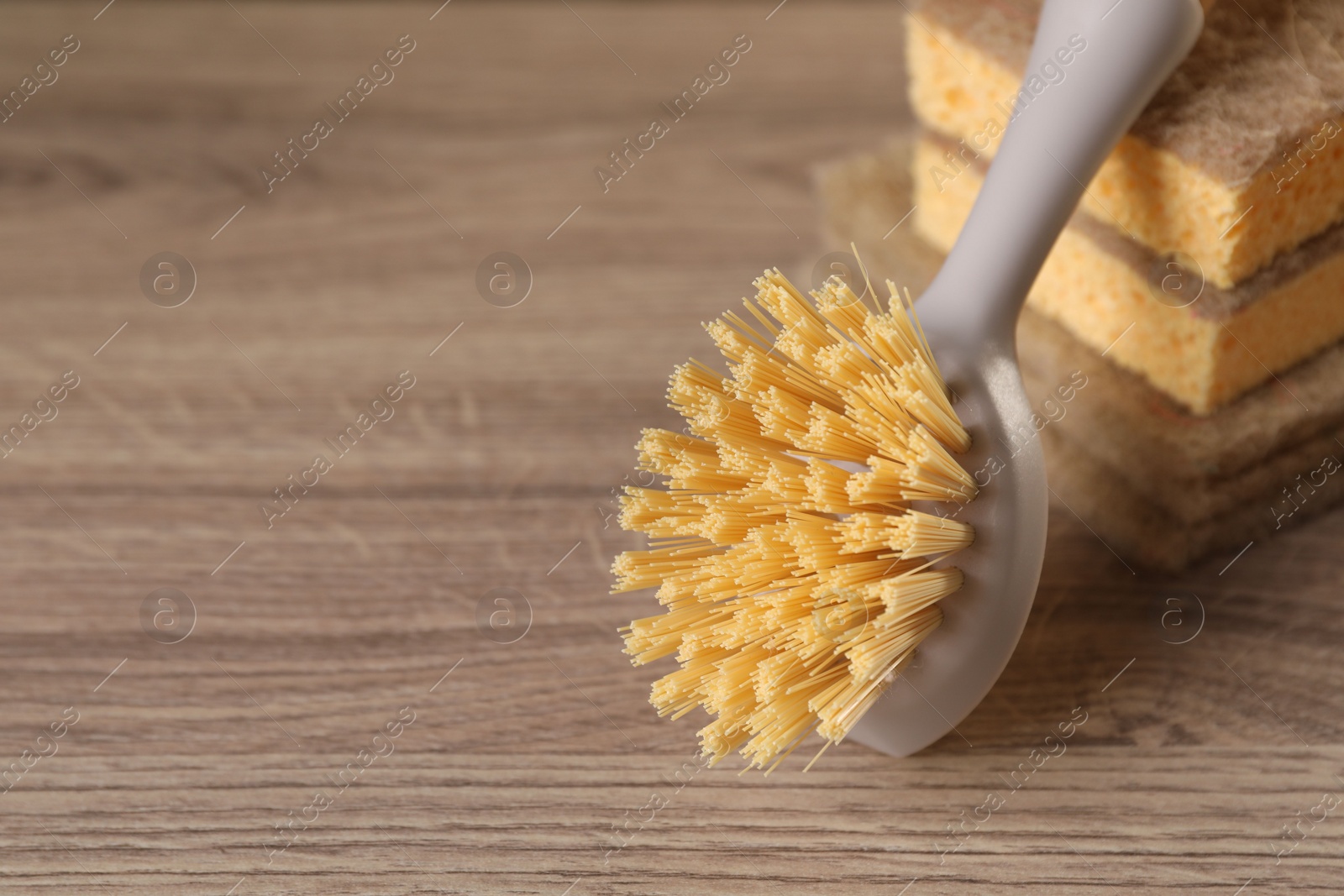 Photo of Cleaning brush and sponges on wooden table, closeup. Space for text