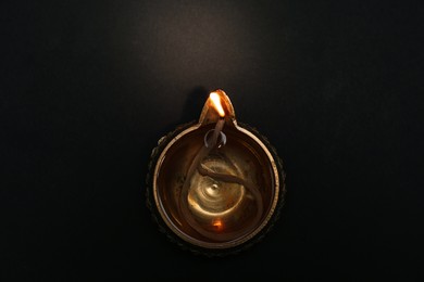Photo of Lit diya on dark background, top view. Diwali lamp