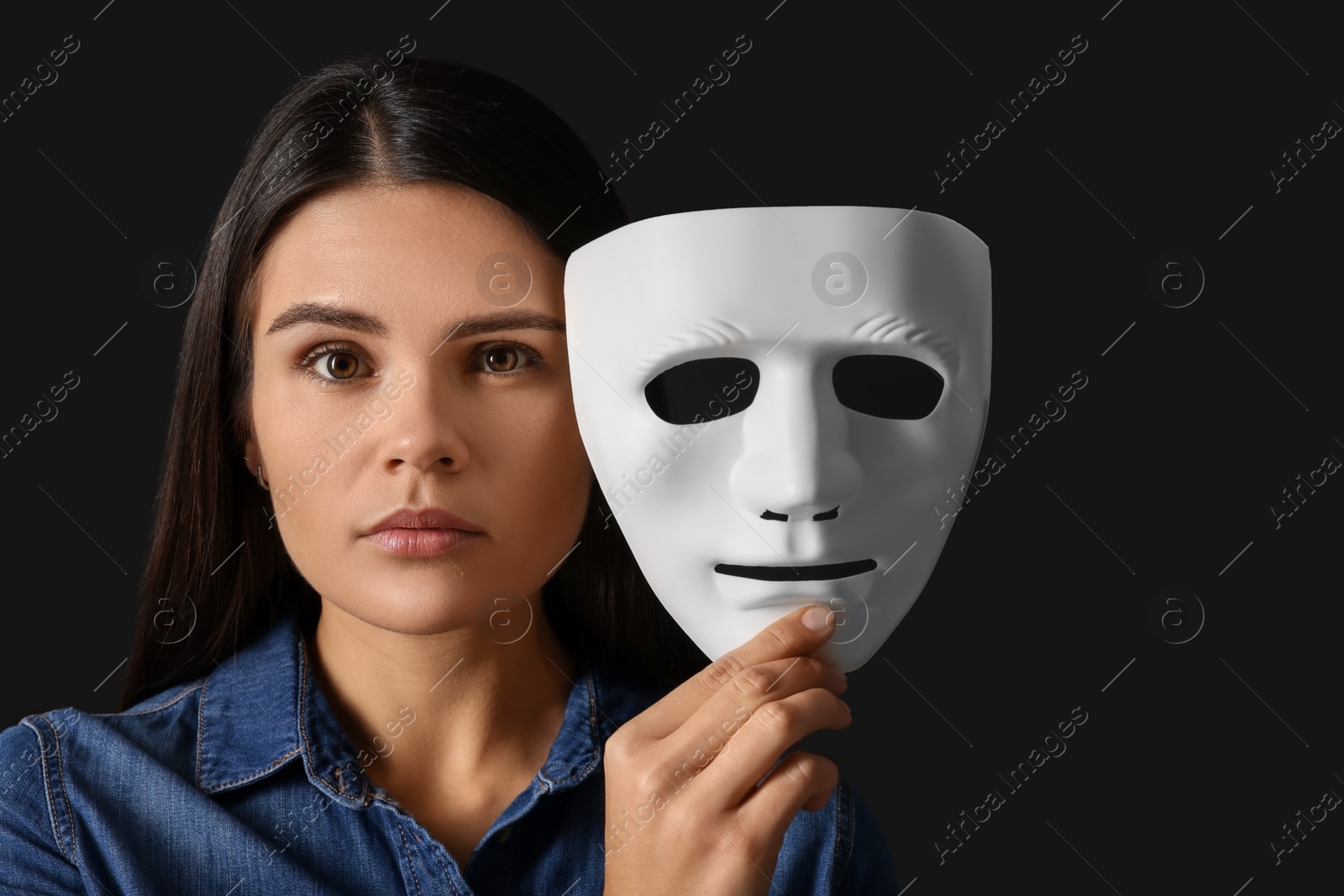 Photo of Multiple personality concept. Woman with mask on black background, space for text