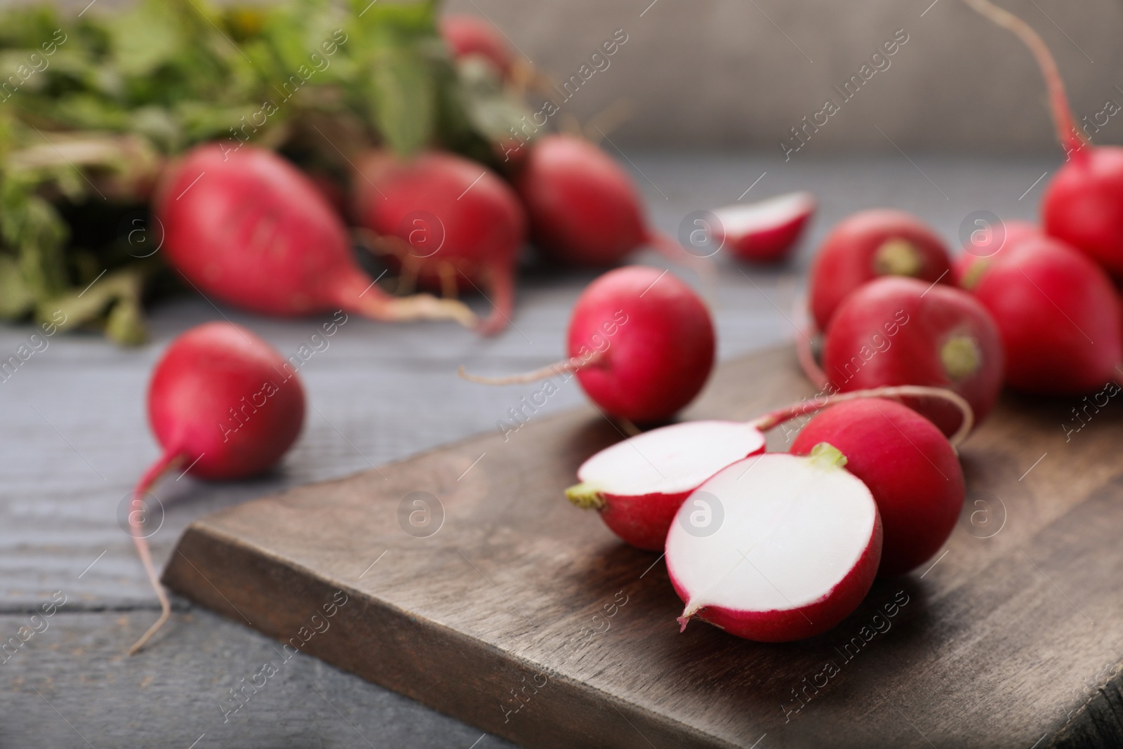 Photo of Fresh ripe radishes on grey wooden table, closeup. Space for text