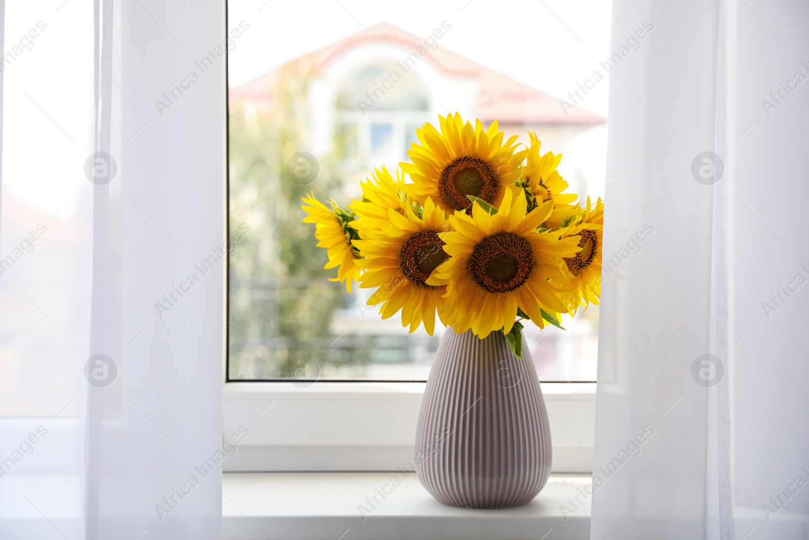 Photo of Bouquet of beautiful sunflowers on window sill indoors