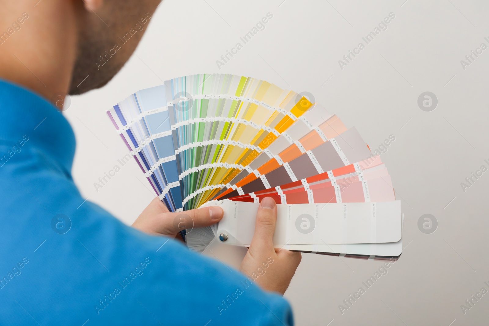 Photo of Man with palette choosing color for painting wall indoors, closeup. Interior design