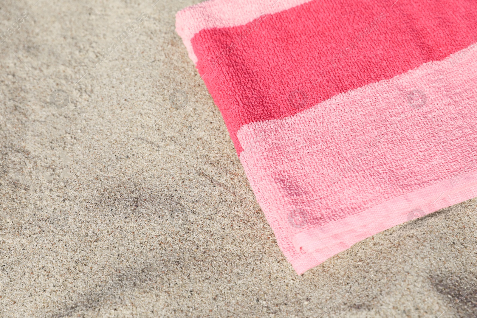 Photo of Soft pink beach towel on sand, space for text