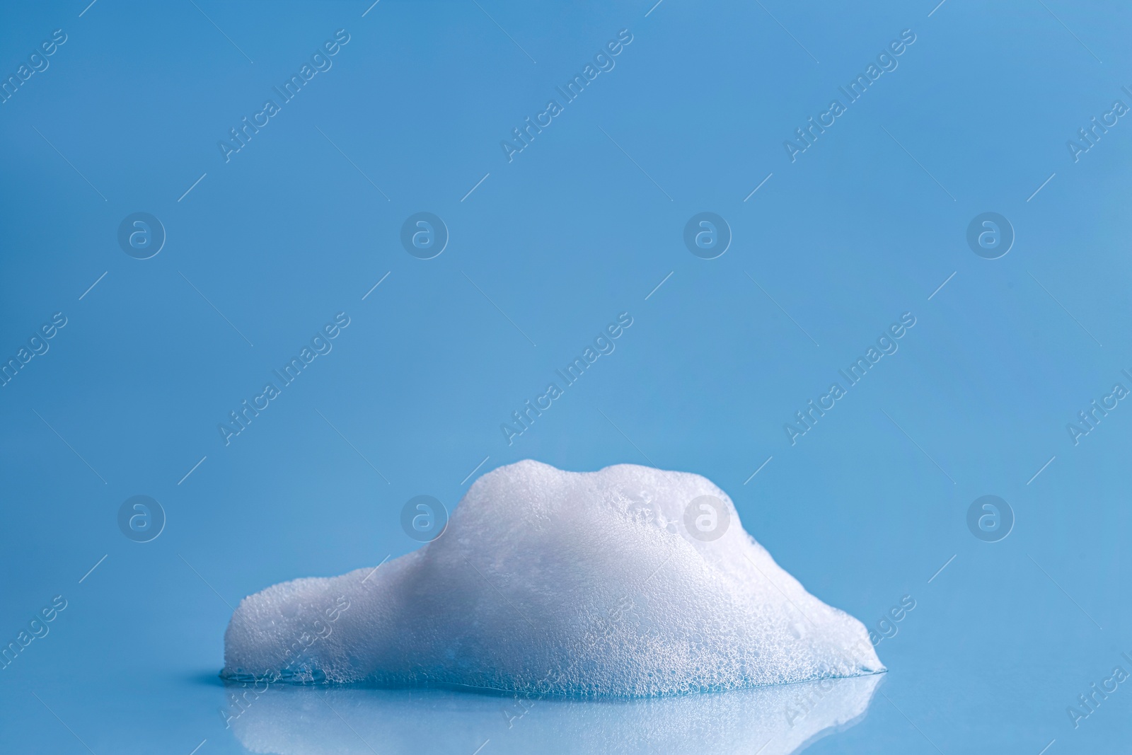 Photo of Fluffy white foam on light blue background, space for text