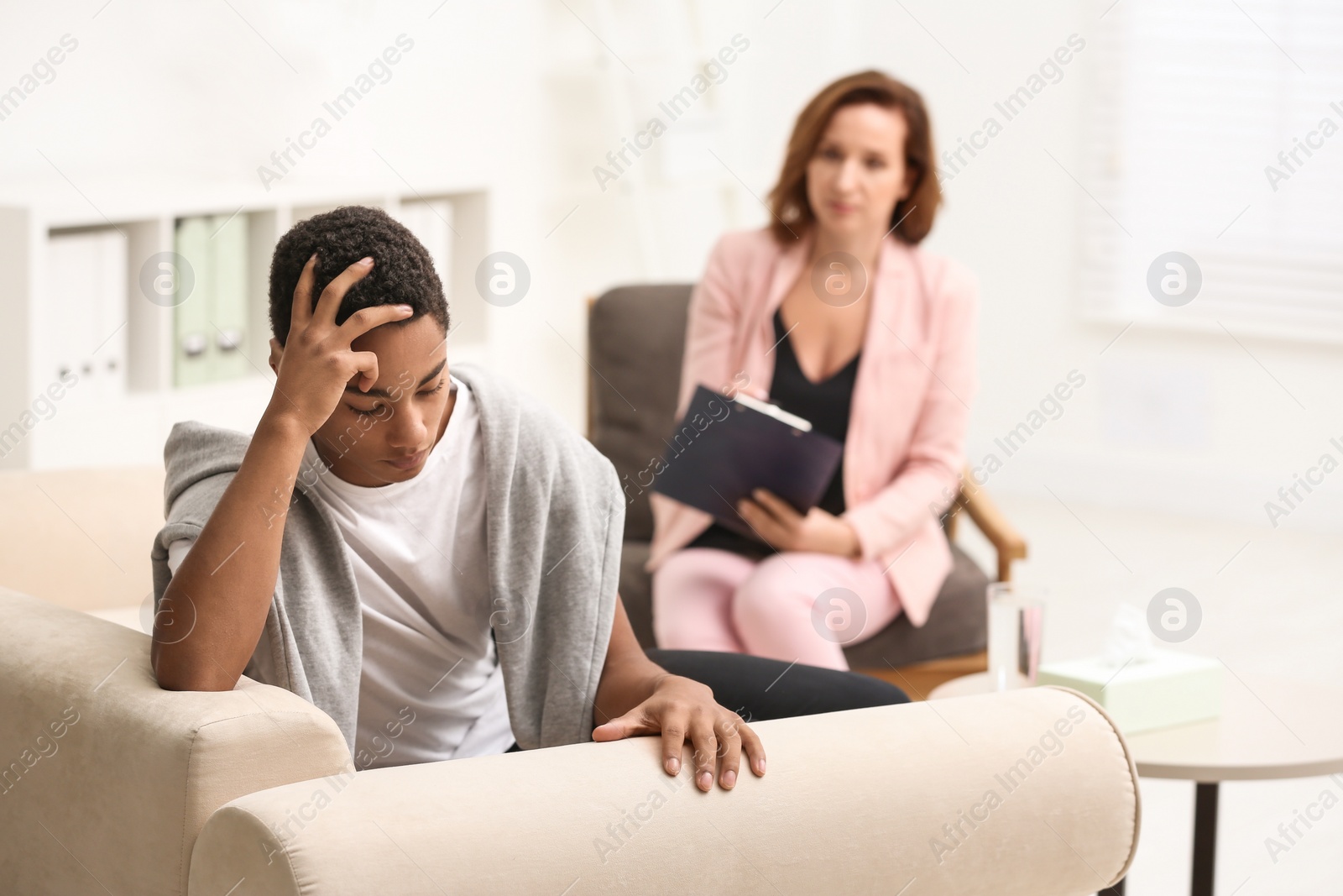 Photo of Psychotherapist working with teenage African-American boy in office