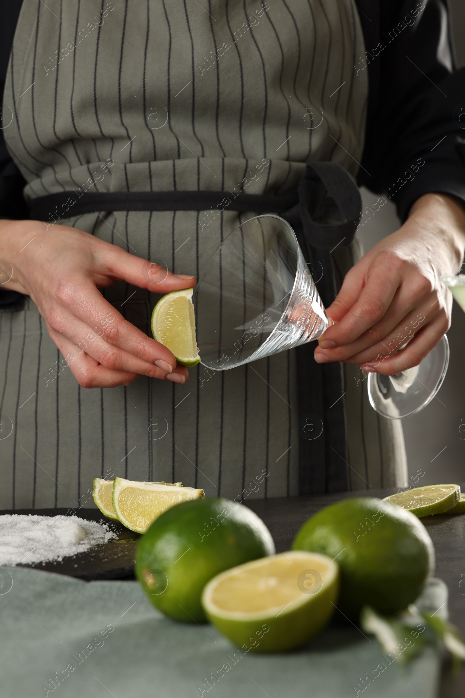 Photo of Woman making delicious Margarita cocktail at grey table, closeup