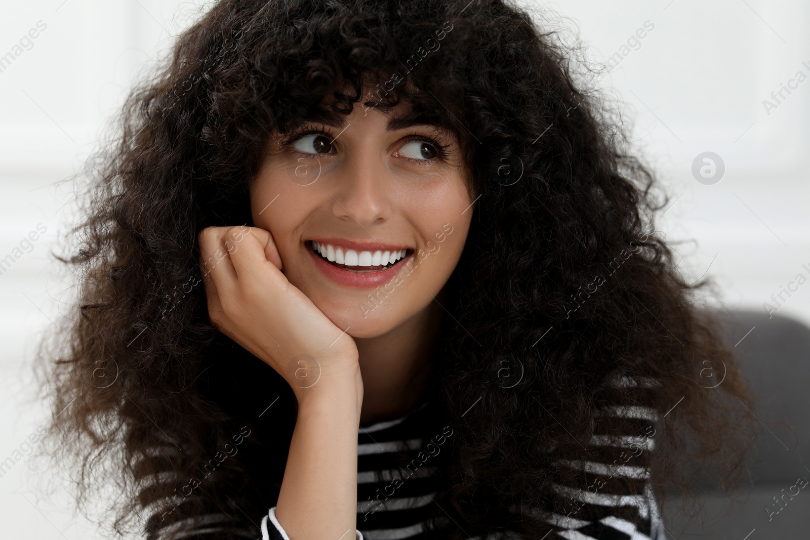 Photo of Portrait of beautiful woman with curly hair on blurred background. Attractive lady smiling and posing for camera