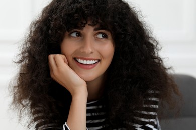 Photo of Portrait of beautiful woman with curly hair on blurred background. Attractive lady smiling and posing for camera