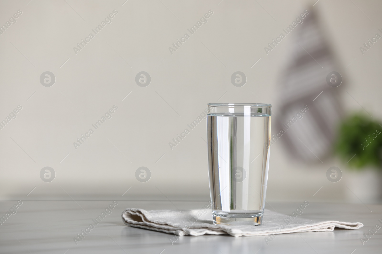 Photo of Glass of pure water on white table indoors, space for text