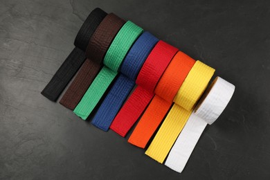 Photo of Colorful karate belts on gray background, flat lay