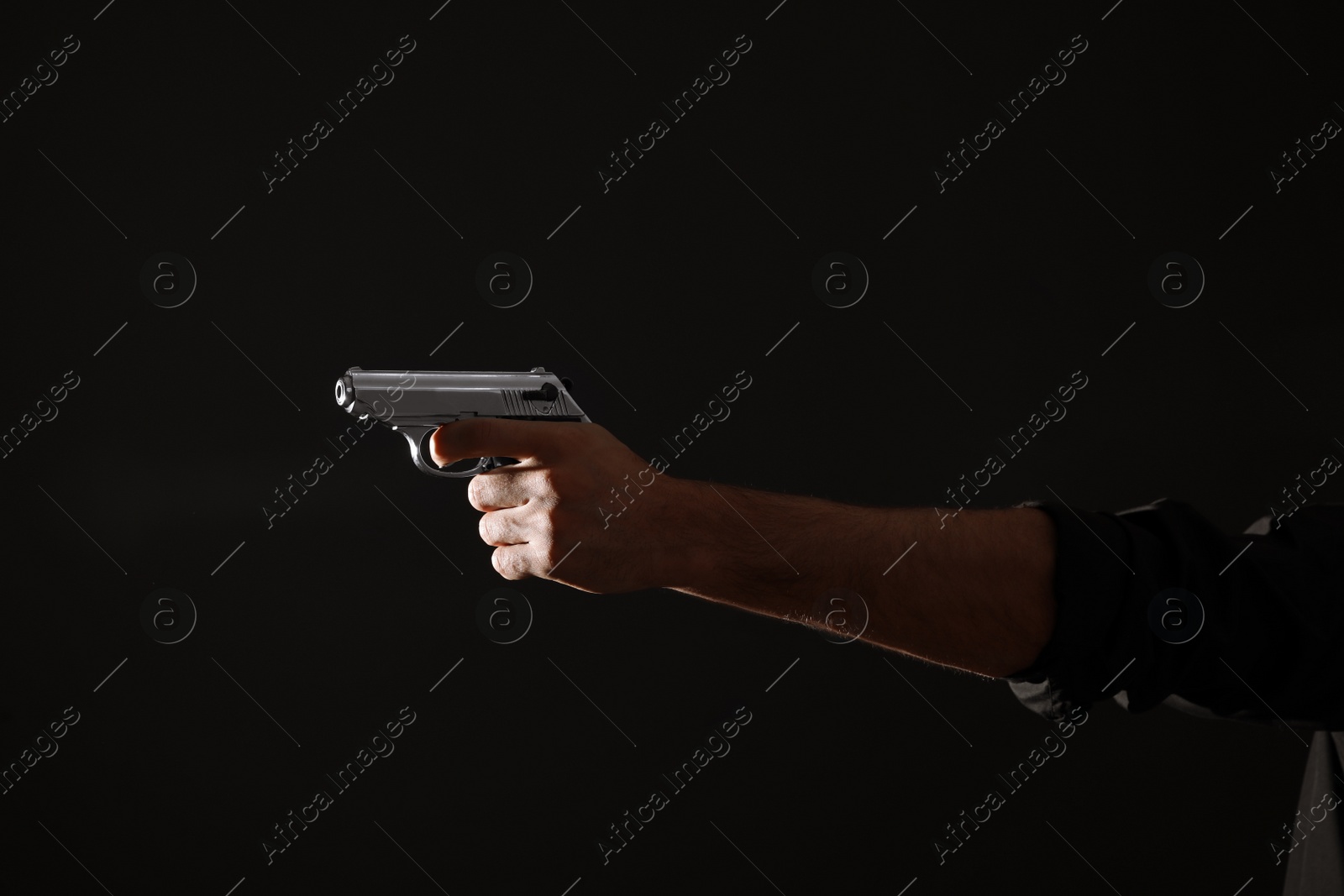 Photo of Professional killer with gun on black background, closeup