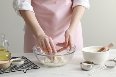 Photo of Woman making dough for traditional grissini at white wooden table indoors, closeup