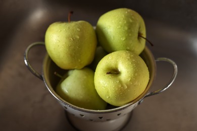 Photo of Fresh wet apples in metal colander inside sink