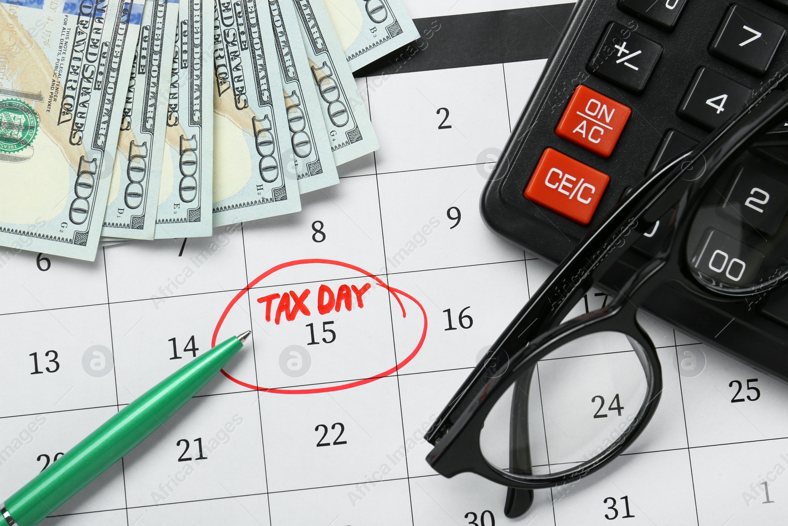 Photo of Calendar with date reminder about tax day, pen, glasses, money and calculator, top view