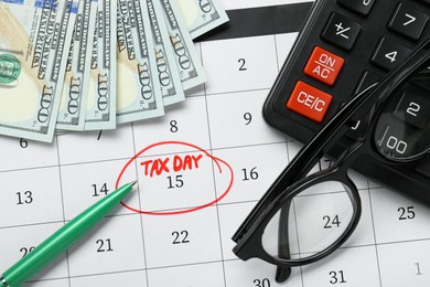 Calendar with date reminder about tax day, pen, glasses, money and calculator, top view