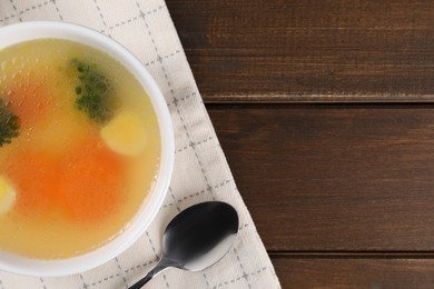 Photo of Tasty soup with vegetables in bowl served on wooden table, top view. Space for text